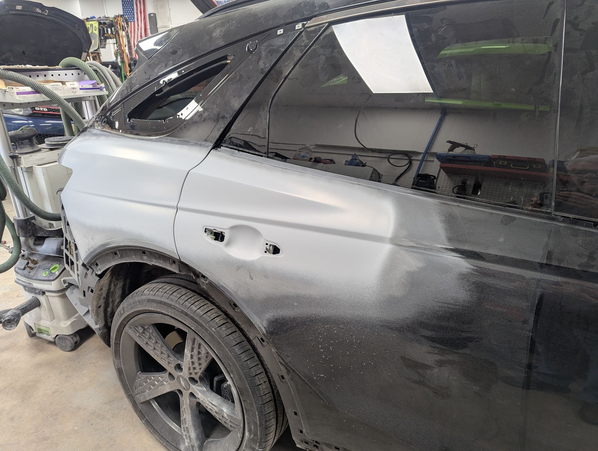 A black car is being painted in a garage.