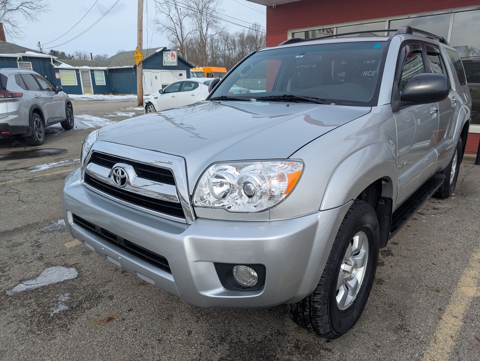 A silver toyota 4runner is parked in a parking lot in front of a building.