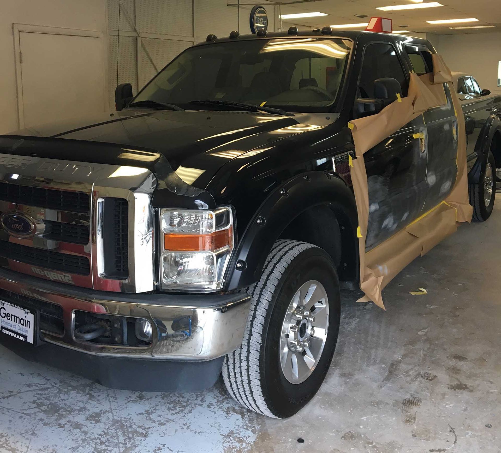 A black ford truck is wrapped in brown paper in a garage