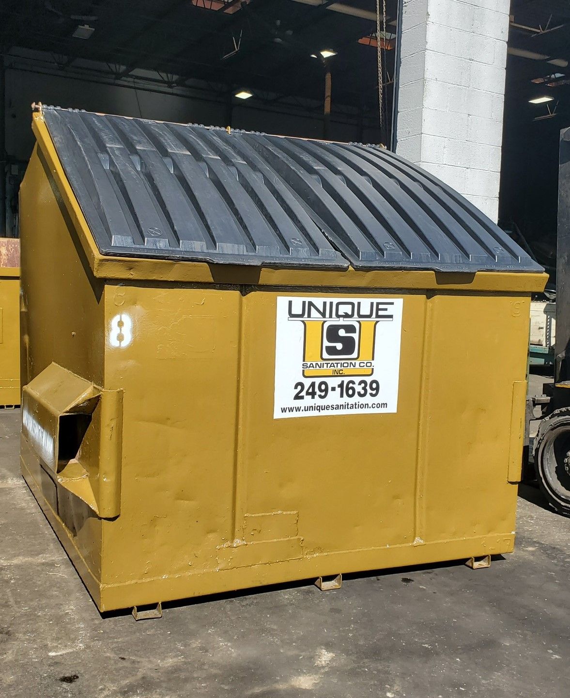 A yellow dumpster that says unique s on it