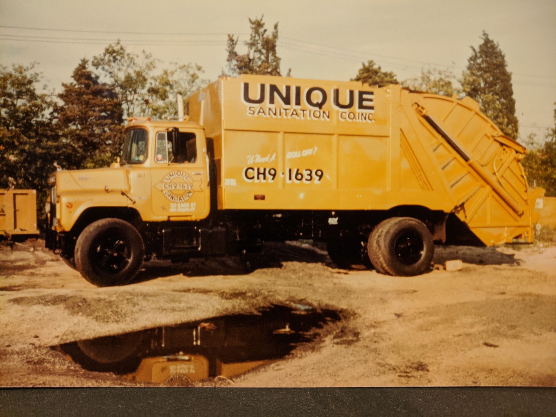 A yellow garbage truck from unique sanitation company