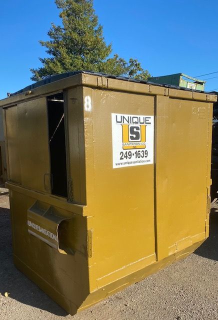 A yellow dumpster that says unique s on it