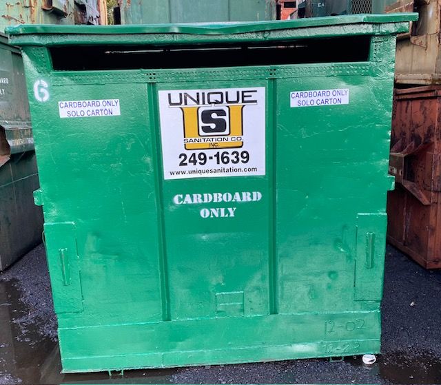 A green dumpster that says cardboard only on it