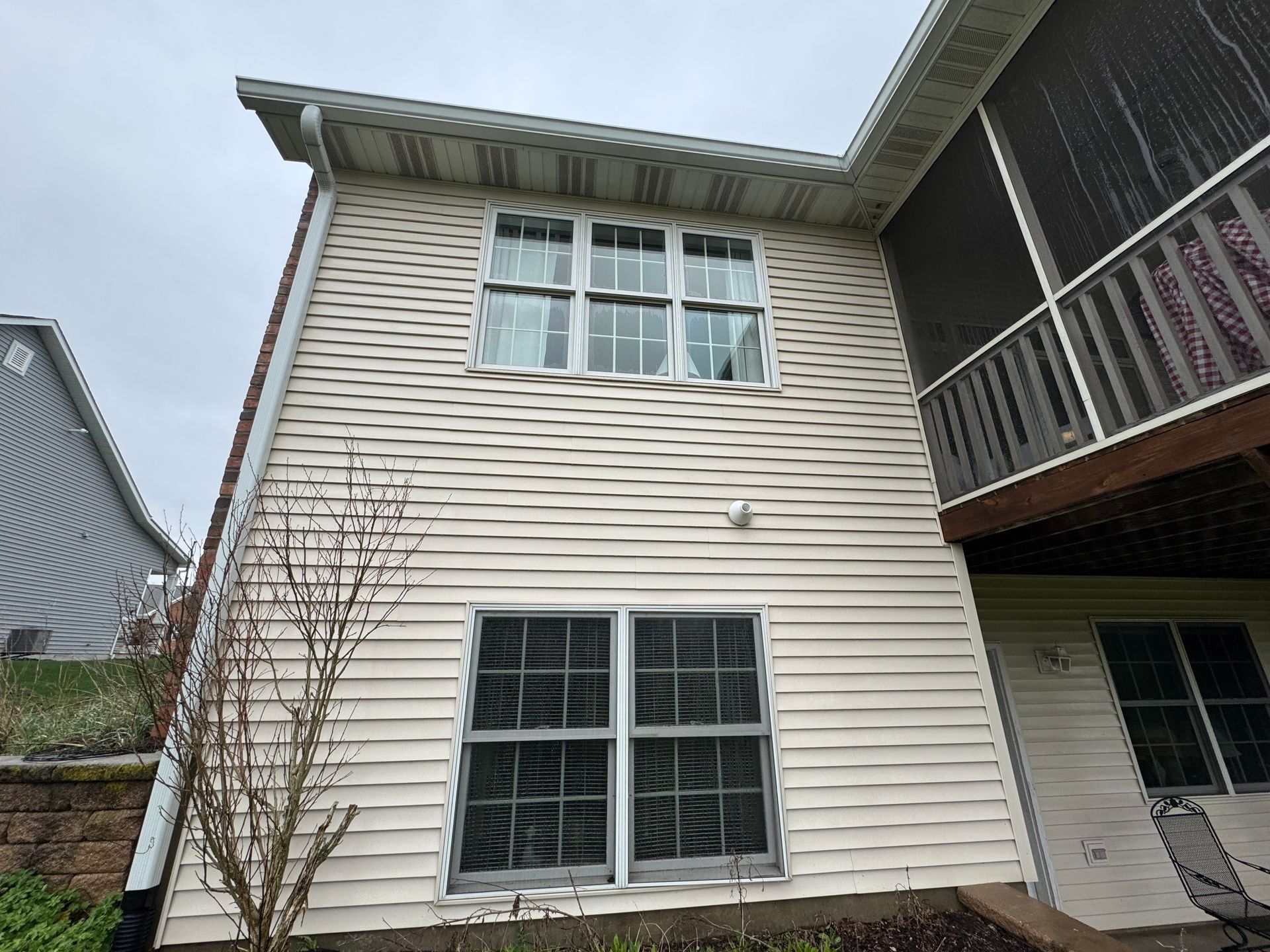Exterior of a two-story house with white siding, multiple windows, and a screened porch.