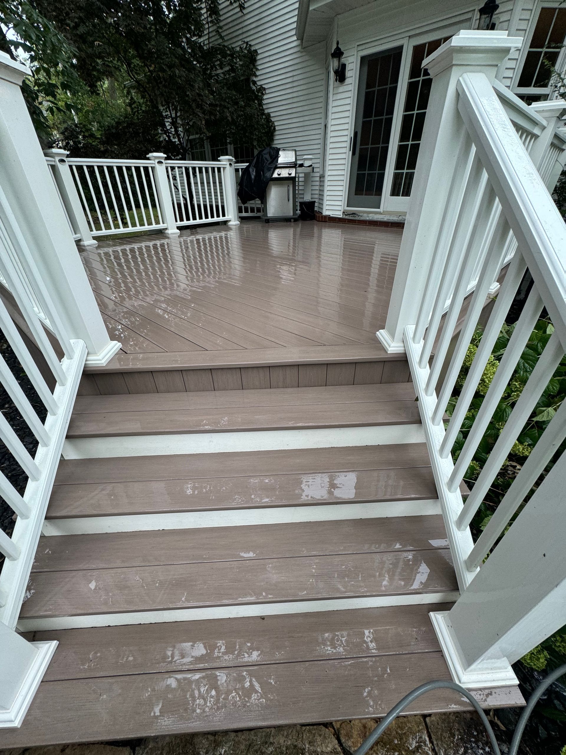 A composite deck staircase with white railings, recently power washed.