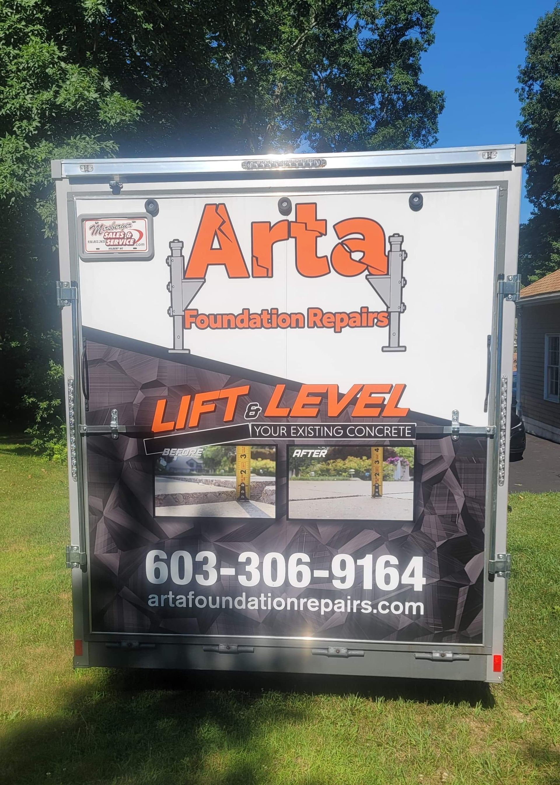 A utility trailer parked on grass features branding for Arta Foundation Repairs with a phone number and website.