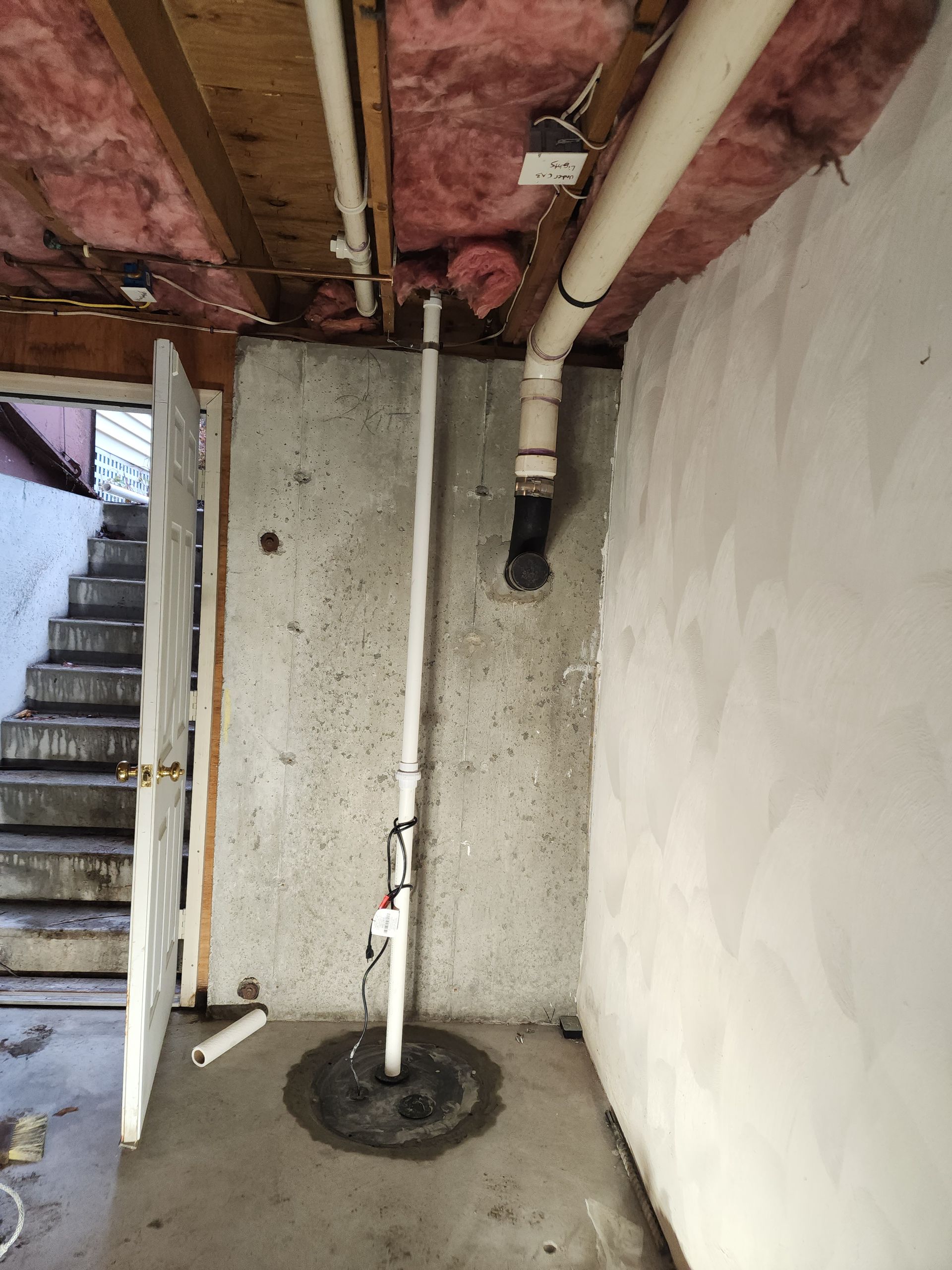 Basement with a central support pole, exposed pipes, and a blue water heater against the wall.