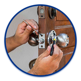 a locksmith fixing a door knob with a screwdriver