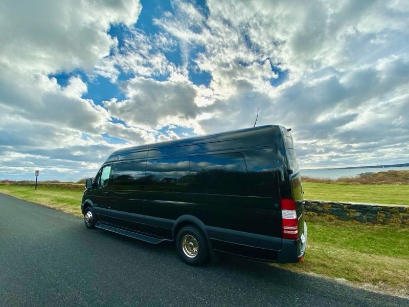 A black van is parked on the side of a road.