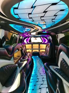 The inside of a limousine with purple and blue lights on the ceiling.
