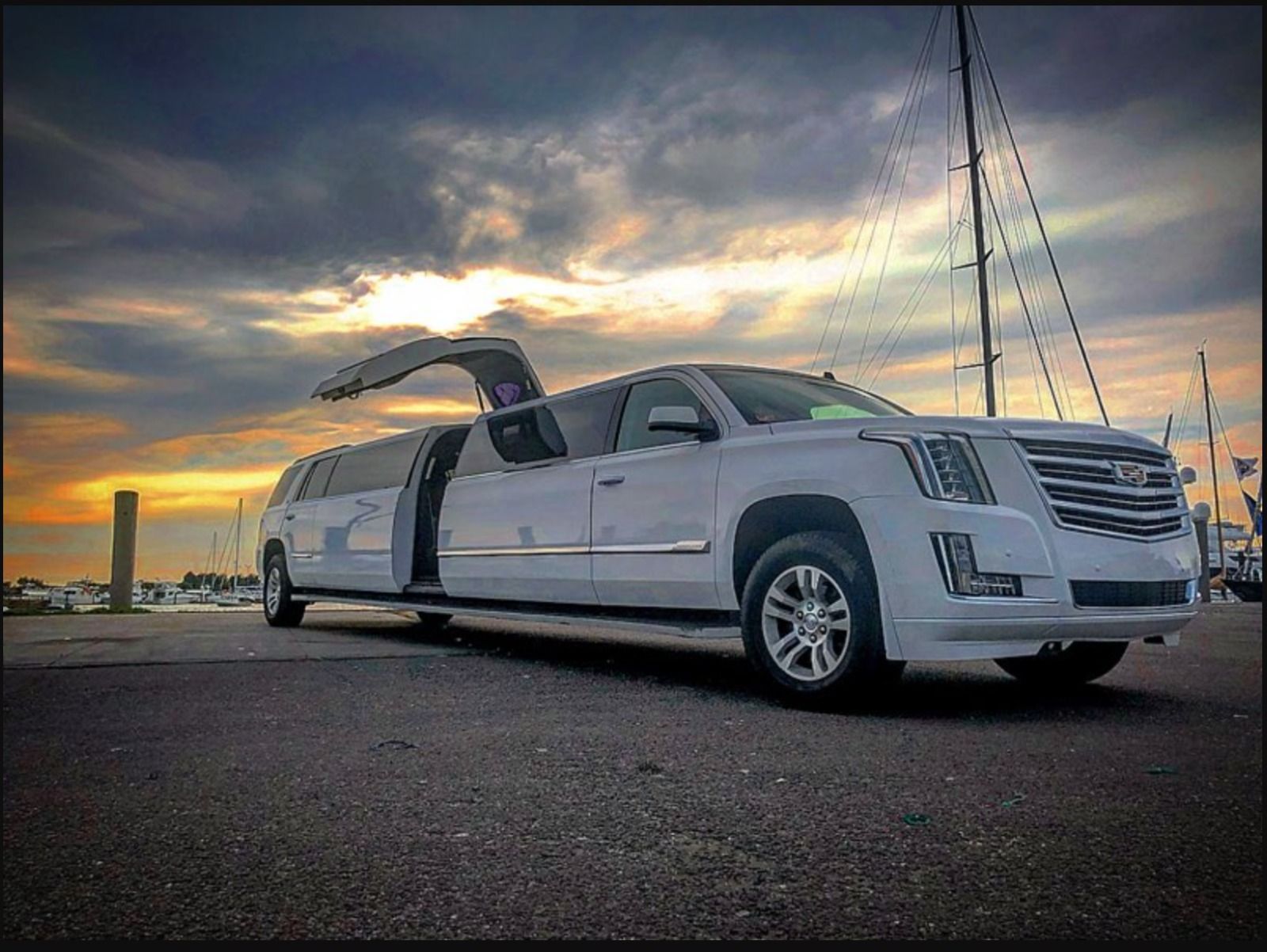 A white limousine with its doors open is parked on the side of the road.