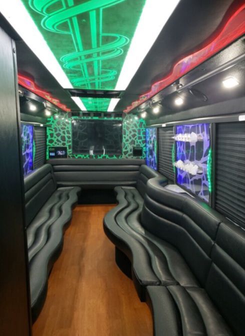 The inside of a bus with a green and white lights on the ceiling.