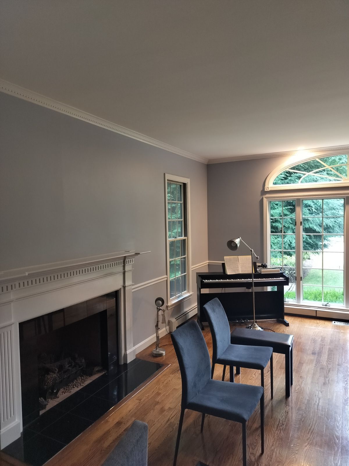 A living room with a fireplace, piano, and chairs