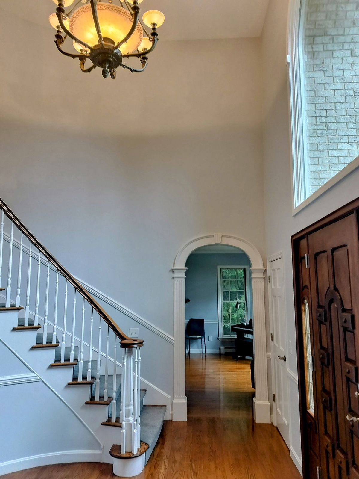 A hallway with stairs and a chandelier hanging from the ceiling