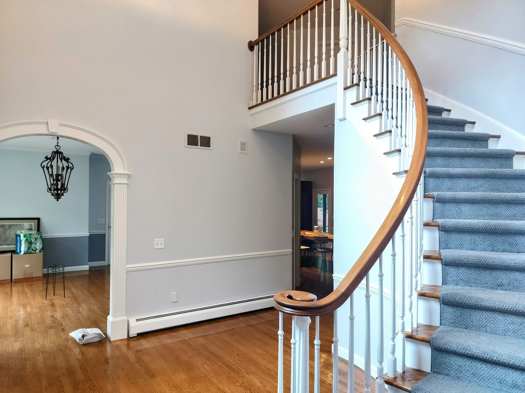 A staircase in a house with a curved railing and carpeted steps.
