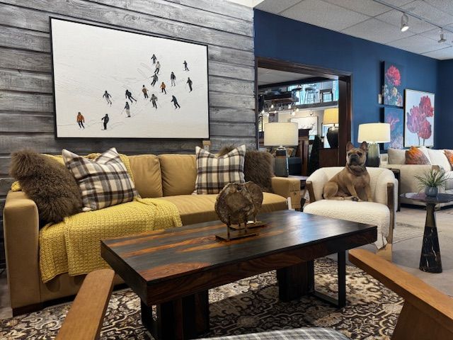 Living room with a yellow couch, skiers art, and a dog in a chair.