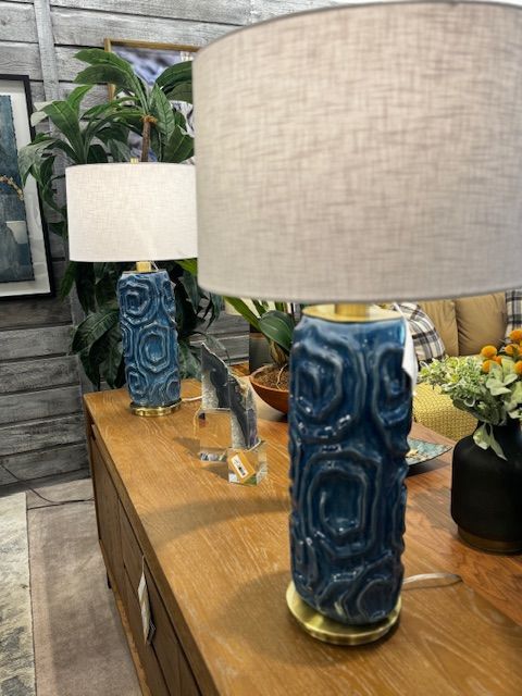 Two blue ceramic lamps with patterned designs on a wooden console table.