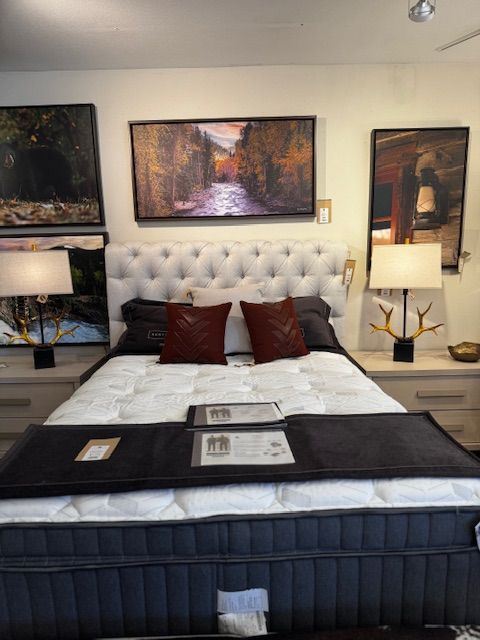 Bedroom with a tufted headboard, art, lamps, and a mattress.