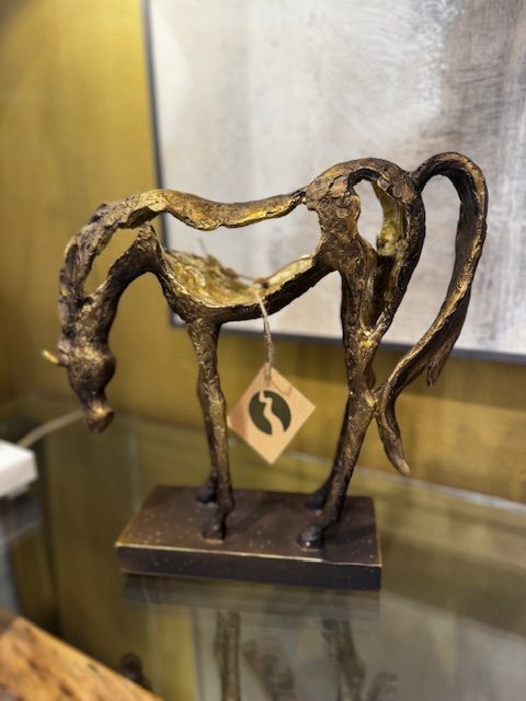 Golden bronze abstract sculpture of a horse, on a dark base, with a tag.