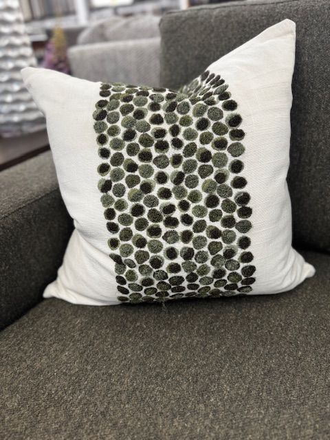 White square pillow with vertical row of green dotted embellishments on a gray sofa.