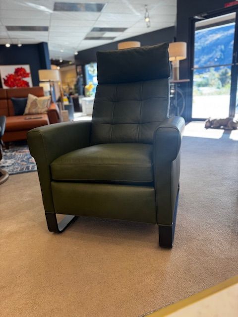 Green leather recliner chair in a showroom setting.