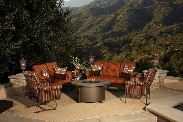 Outdoor patio with orange furniture, fire pit, and mountain view.