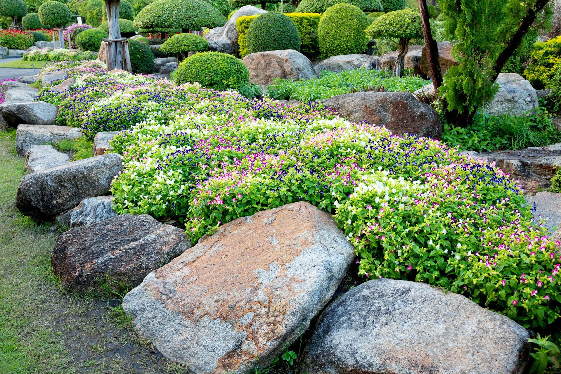 A stone path in a garden surrounded by flowers and grass.