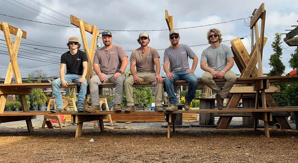 A group of men are sitting on wooden benches.