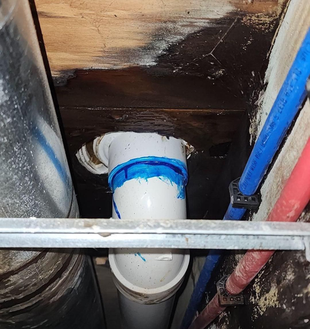 A white pipe with blue tape on it is surrounded by red and blue pipes