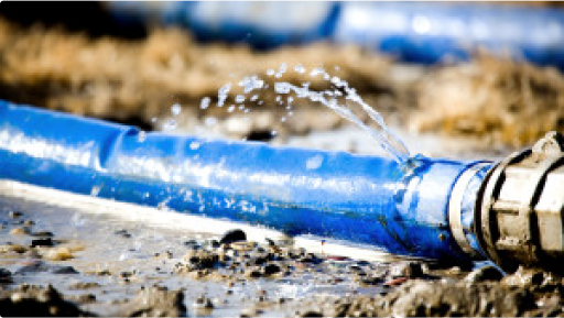 A blue pipe is leaking water on the ground.