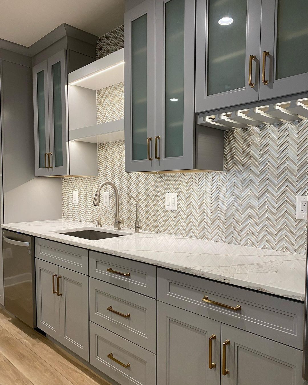 Gray kitchen with glass-front cabinets, white countertops, and a patterned backsplash.