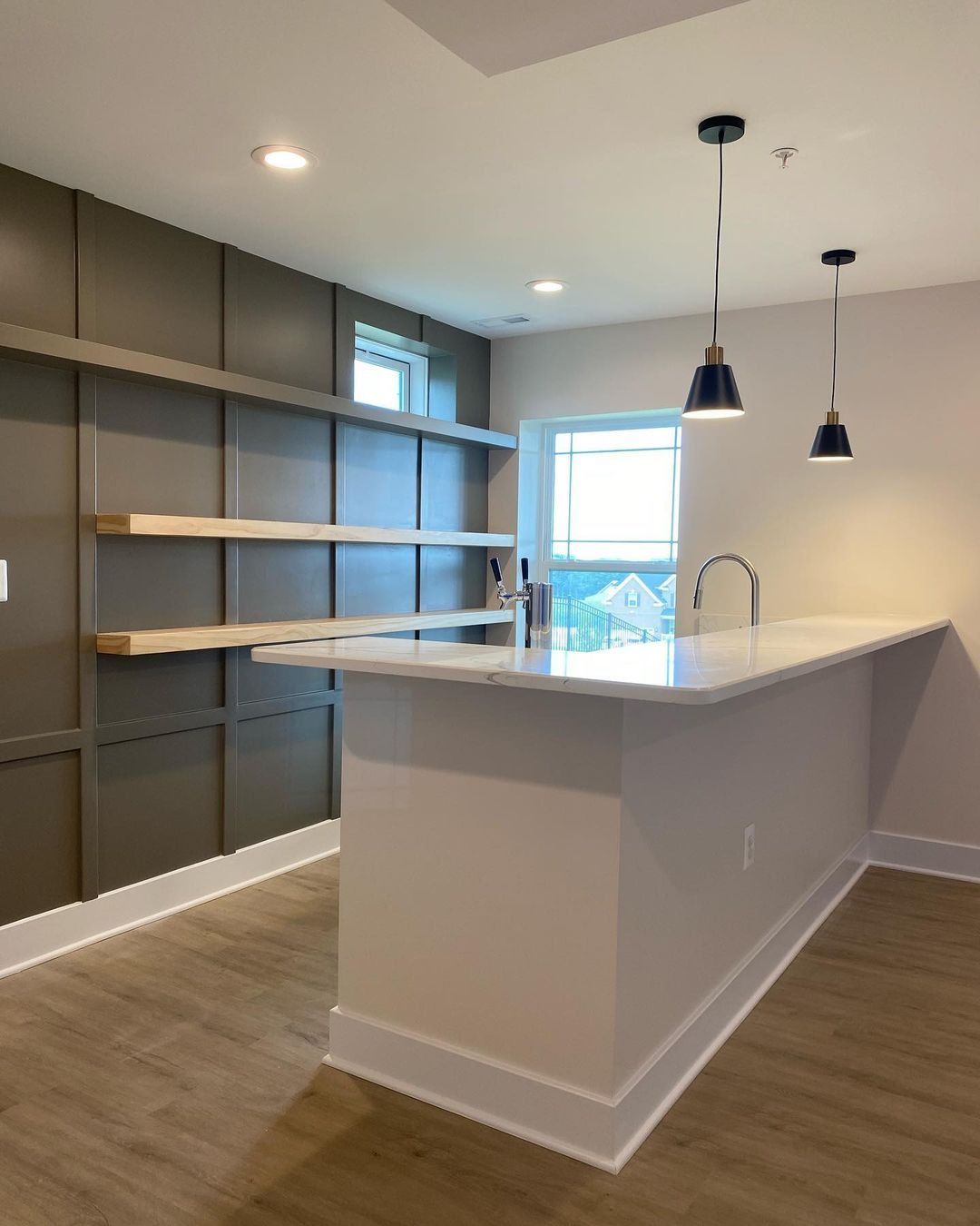 Interior view of a modern kitchen with a breakfast bar, shelving, and two pendant lights.