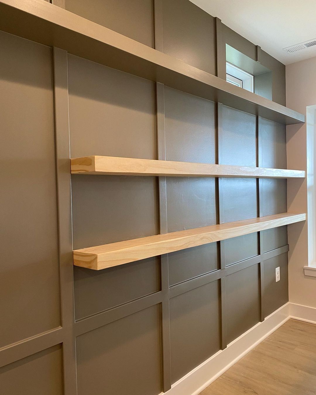 Built-in shelves in a room with brown paneled walls and light wood shelves.