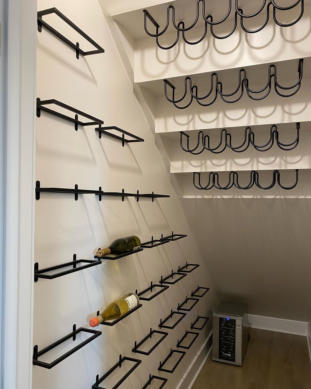 Wine rack built into an angled wall with several bottles on display, and a wine cooler.