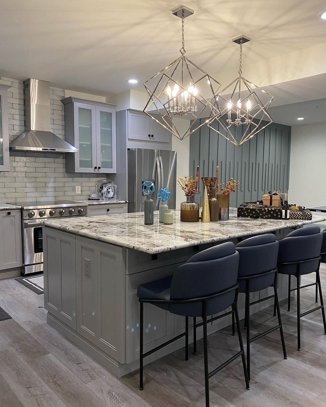 Gray kitchen with island, pendant lights, stainless steel appliances, and bar stools.