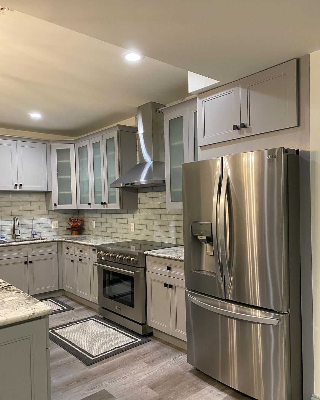 Modern kitchen with stainless steel appliances, gray cabinets, and light wood-look flooring.