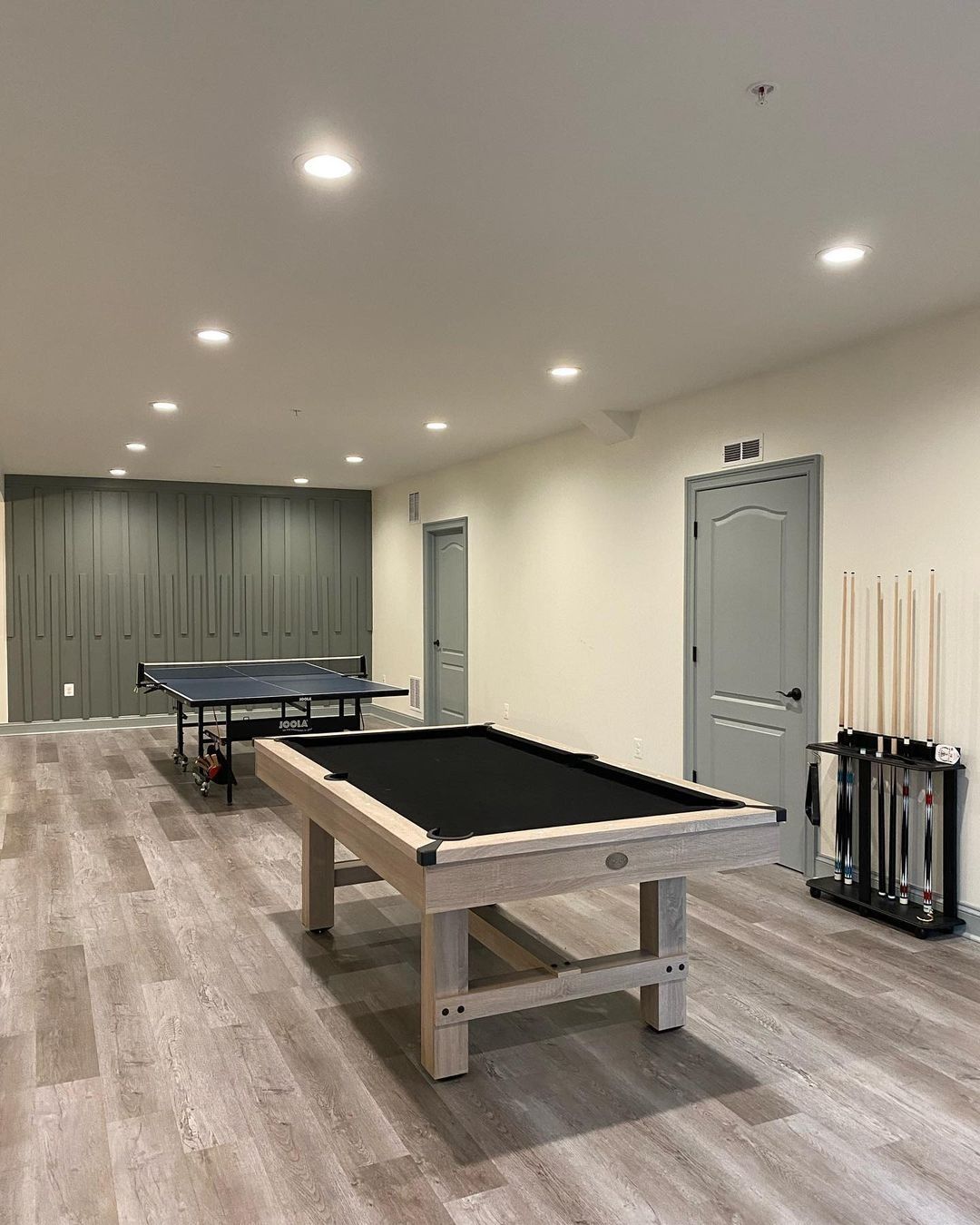 Pool table and ping pong table in a room with light wood floors and gray walls.