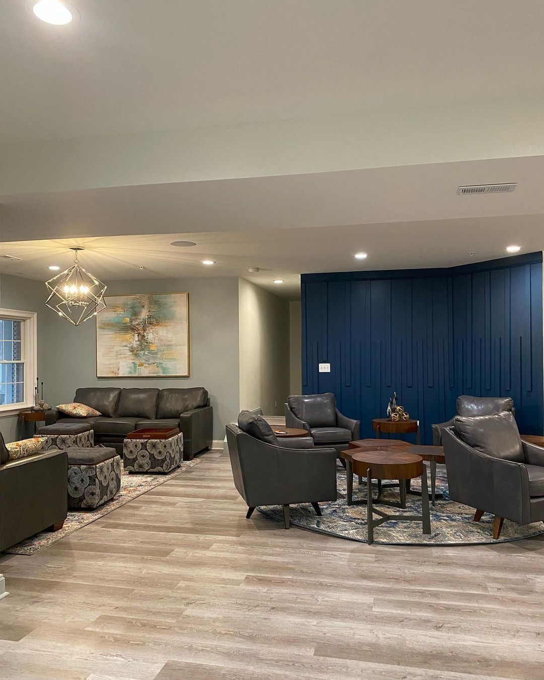 Spacious living room with gray furniture, blue accent wall, and wood-look flooring.