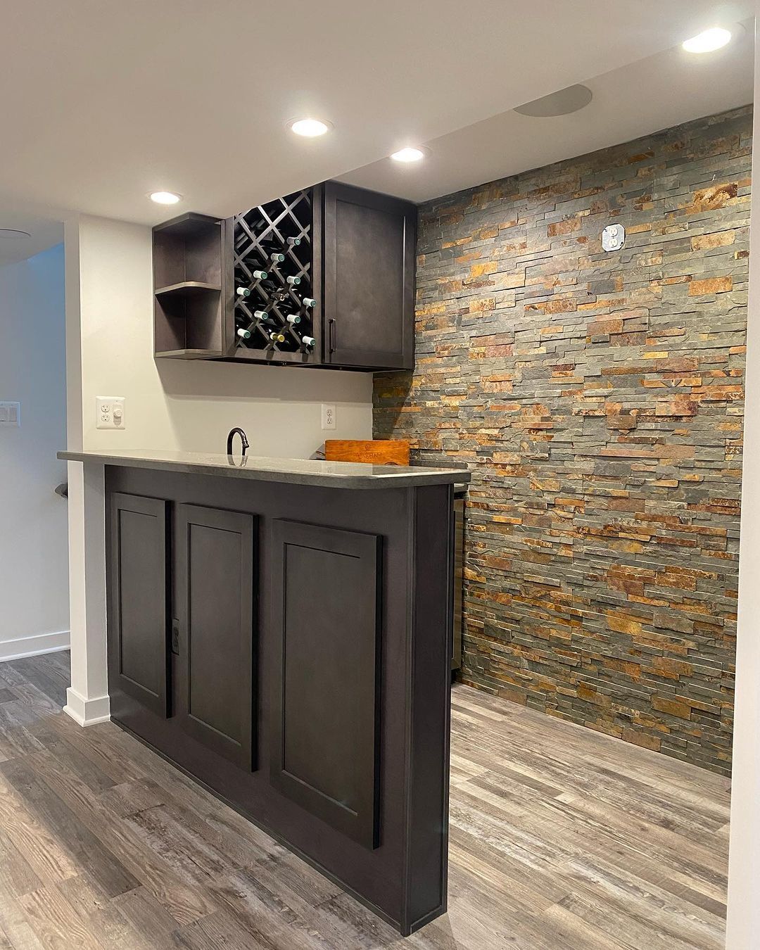 Dark wood bar with brick accent wall; wine rack and sink.