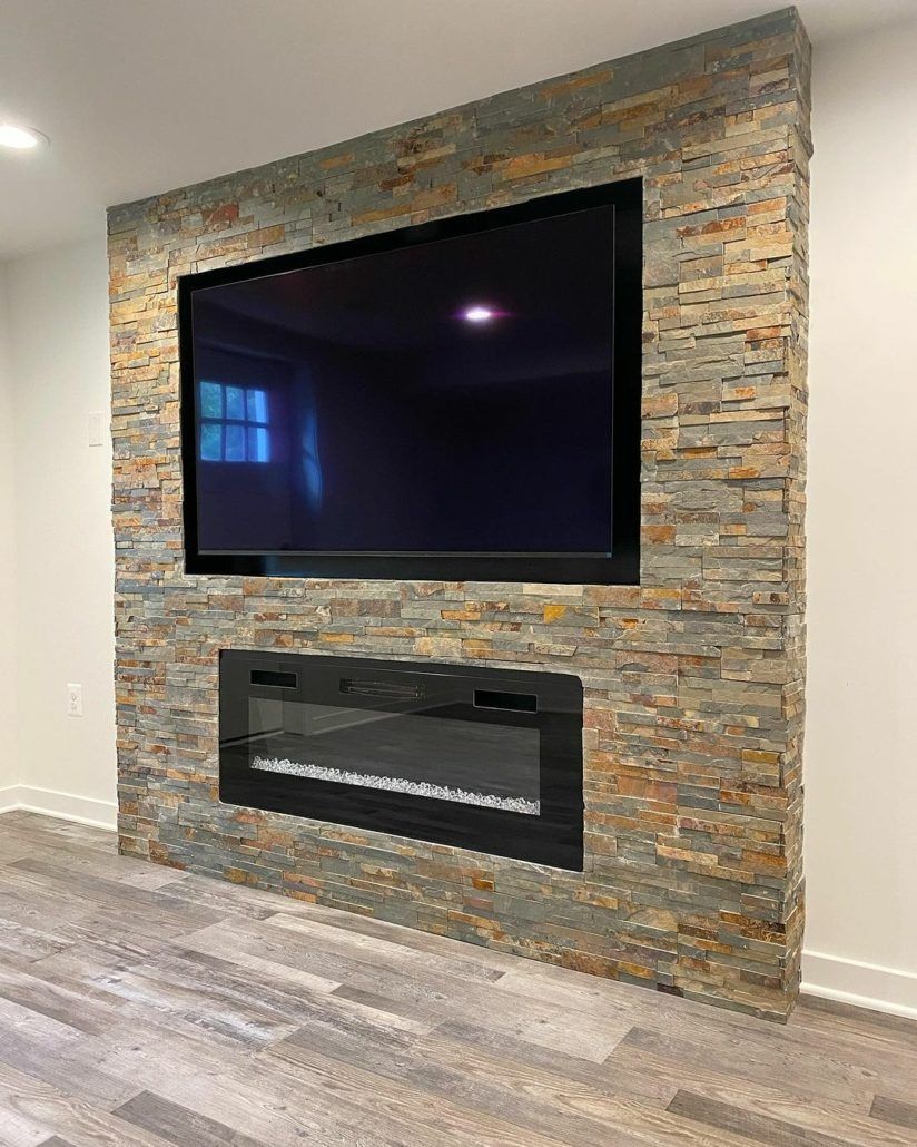 A TV and electric fireplace are built into a stone-covered wall. The room has light flooring.