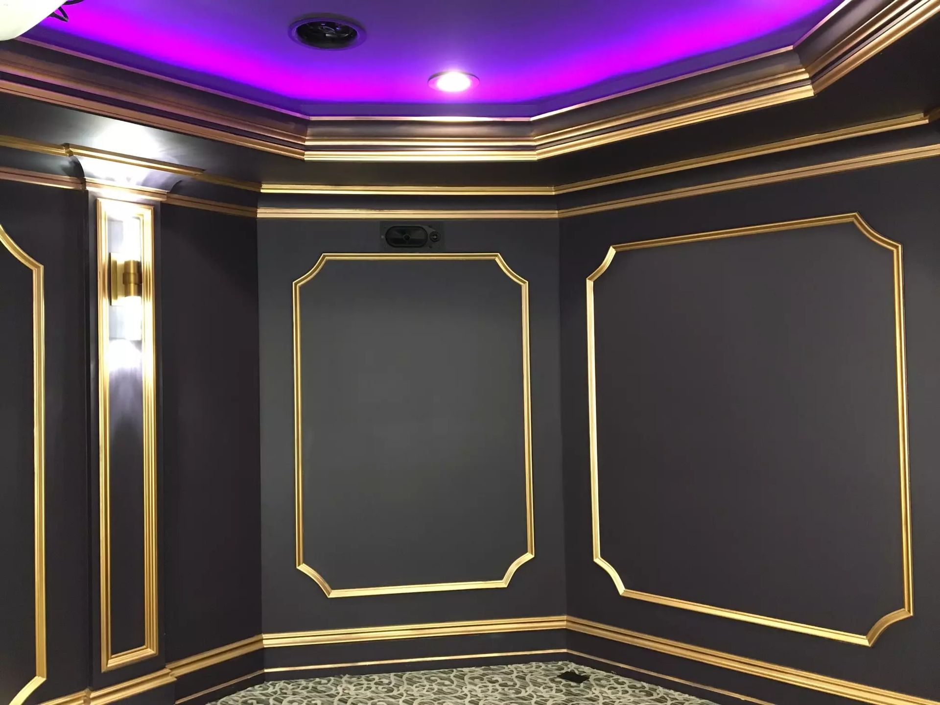 Dark gray room with gold trim and purple ceiling lighting.