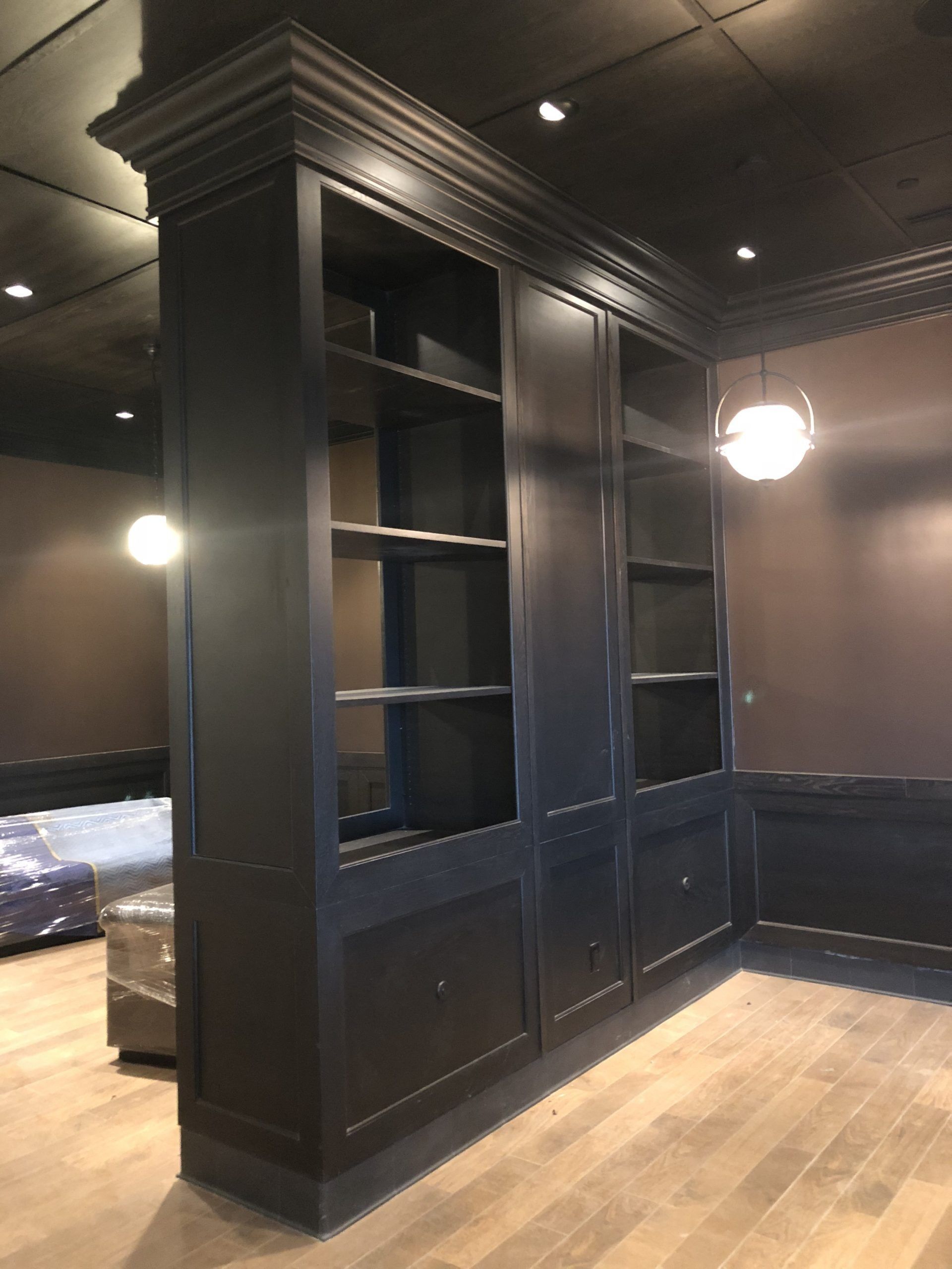 Tall, dark blue built-in bookshelves with crown molding and paneled doors, in a room with a wood floor.