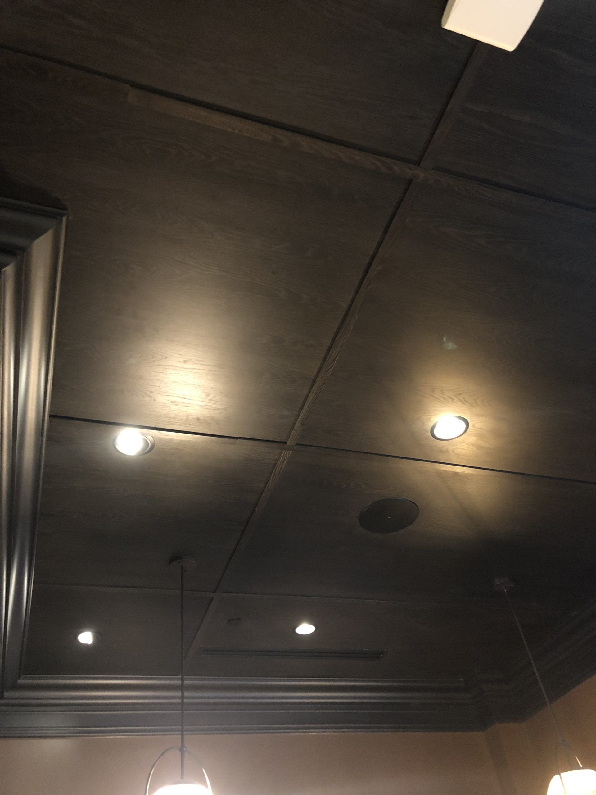 Dark wooden ceiling with recessed lights and decorative trim.