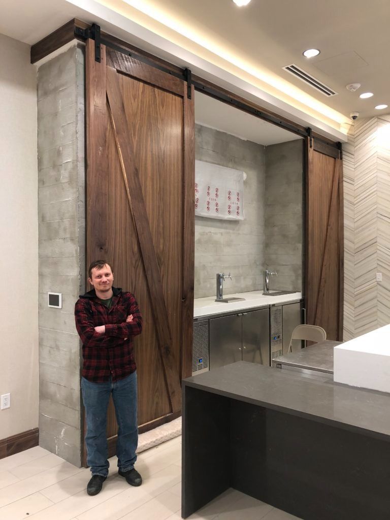 Man stands near closed wooden sliding doors, with a sink area visible in the opening.