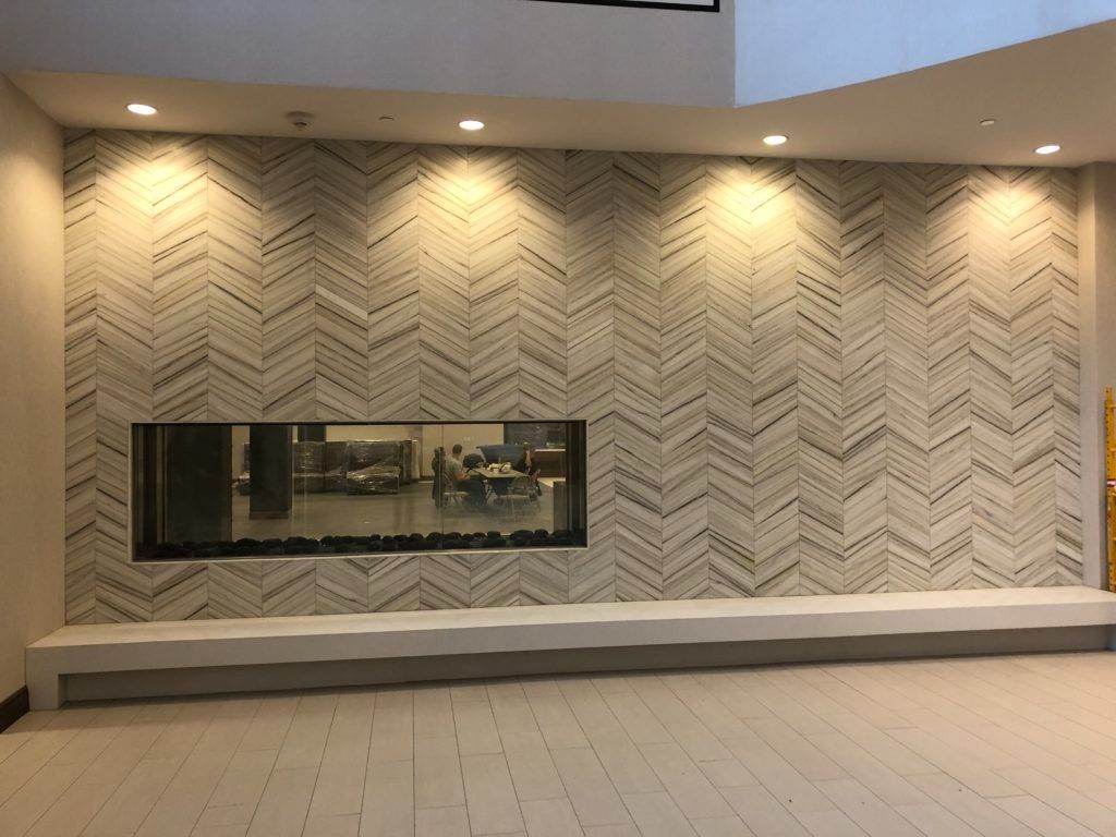 Fireplace with a patterned tile wall, a built-in bench, and recessed lighting. The tile is a light color.