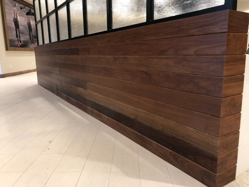 A long, low, wooden wall constructed of horizontal planks; set against a window and light floor.