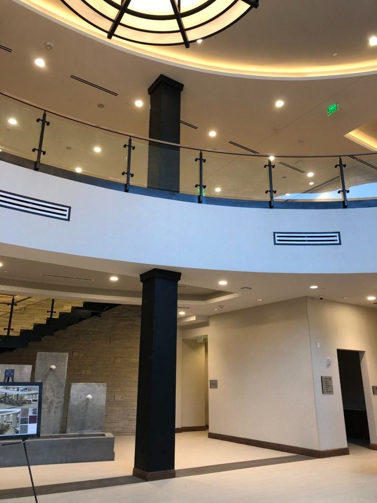 Interior of a modern building with a curved balcony, black columns, and a staircase.