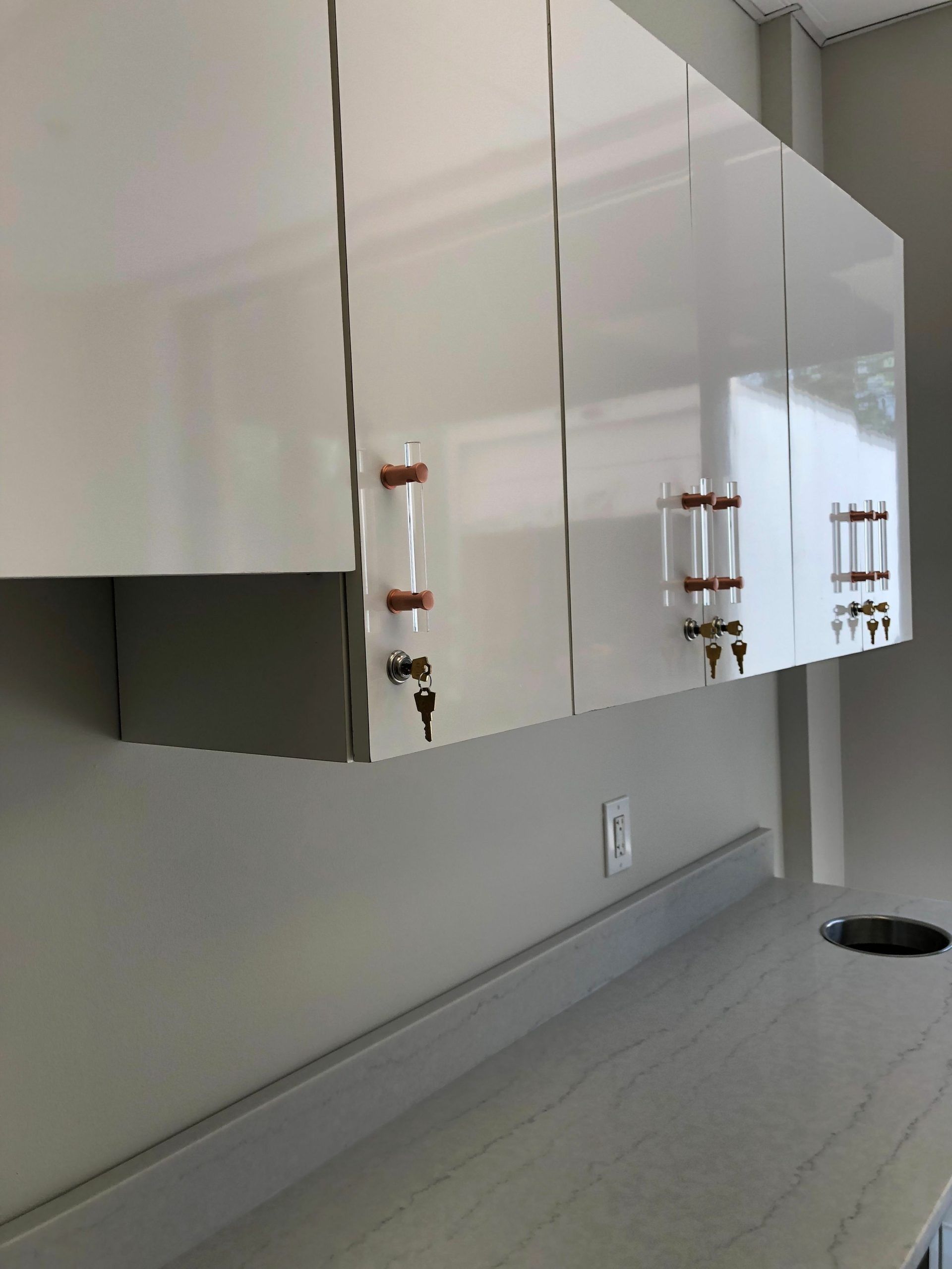 White cabinets with copper handles over a gray countertop.