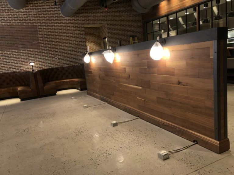 Wooden wall with three hanging lights in a modern interior, concrete floor, and leather booth seating.