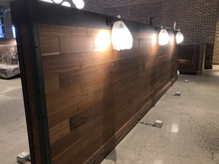 Wooden bar with warm lighting, in a brick-walled room.